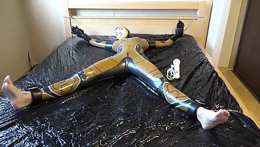 Lateks Danielle yatağa bağlı ve masaj vibratörüyle mastürbasyon yapıyor