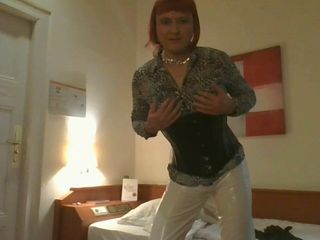 Transexual en pvc blanco está esperando en la habitación del hotel