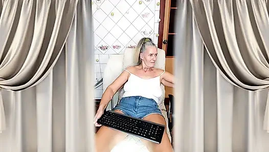 Fröhliche hausfrau Lukerya flirtet in engen jeansshorts in der küche.