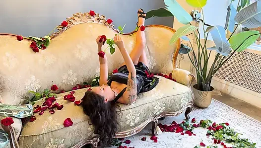 Schöne monika fox im schwarzen kleid auf sofa mit rosen