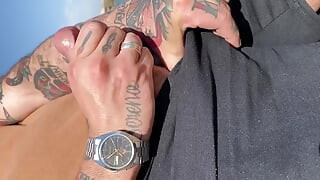 Un homme tatoué fait une branlette dehors