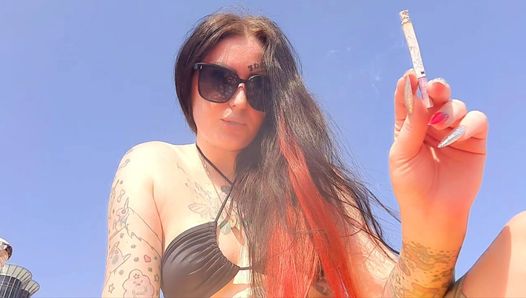 Palenie fetyszu. Dominatrix pali papierosa na plaży