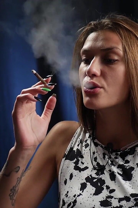 Slim Brunette in a Patterned Dress Smoking Slowly with a Calm and Confident Attitude