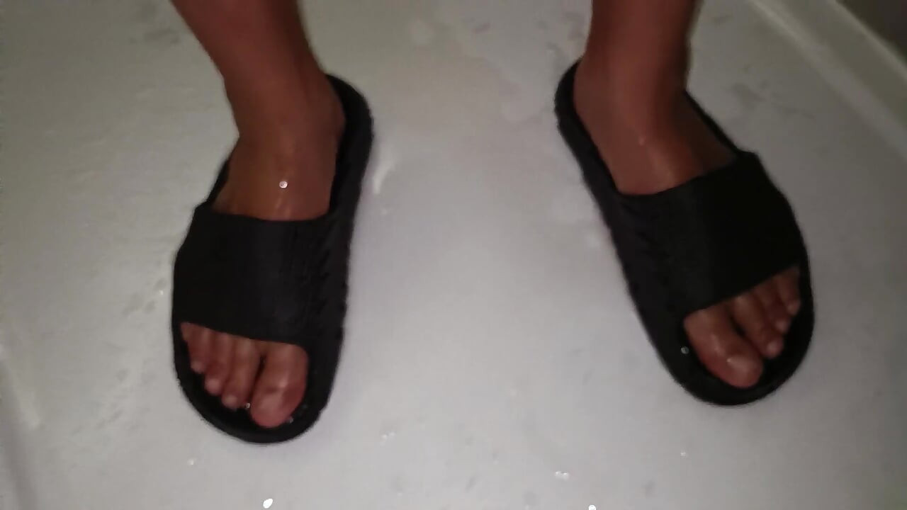 Mijo nos pés em slides de sandálias enquanto usa troncos brancos de natação