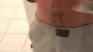 Lateinischer Junge, der strippt und mit Schwanz im Badezimmer spielt