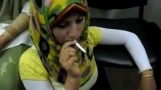 Горячая арабская девушка в хиджабе курит сигарету в первый раз