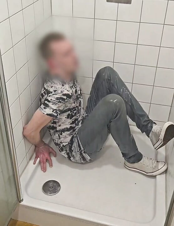 Brincando no chuveiro totalmente vestido com jeans e mandris