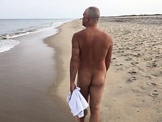 Paseo público por la playa nudista con agacharse