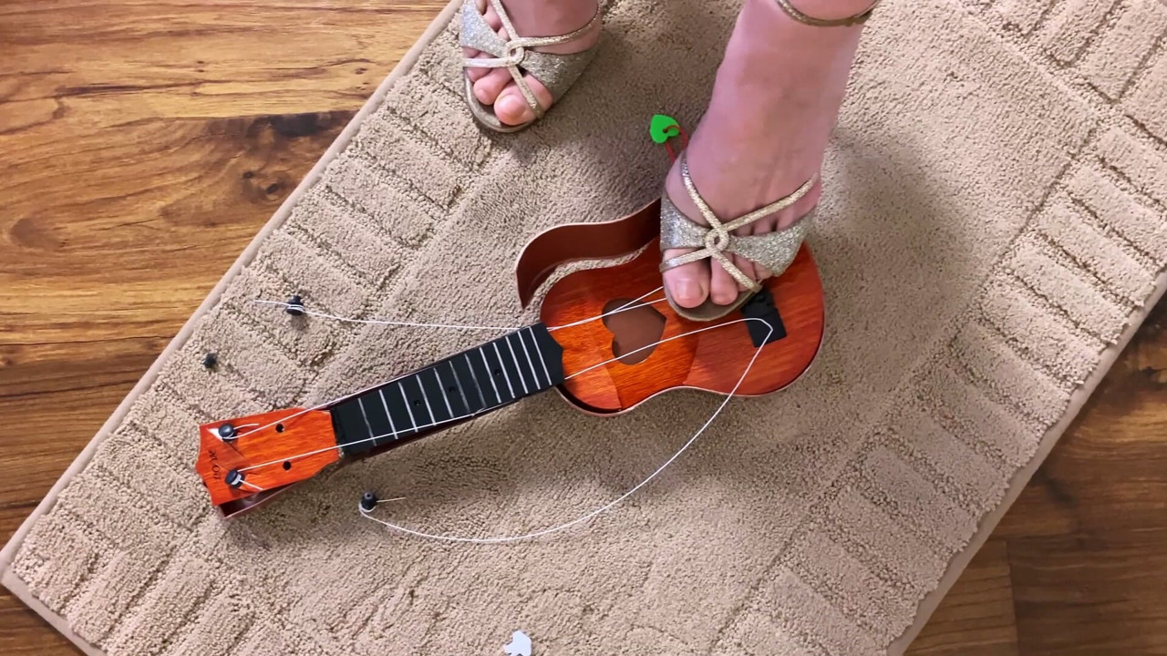 Crushing toy guitar in luxury high heels