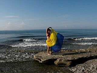 Dançando na praia do mar Mediterrâneo com xale amarelo-azulado