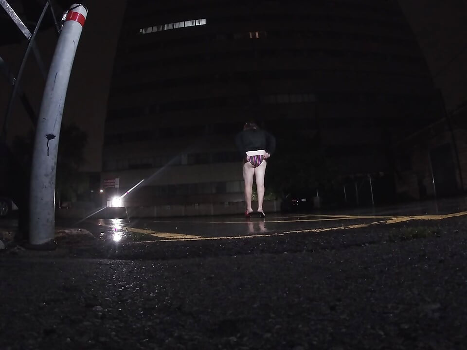 Sissy CD mature sous la pluie dans un parking en train de se masturber en public.