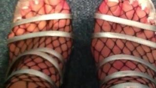 Füße in sexy High Heels und Netzbodystockings