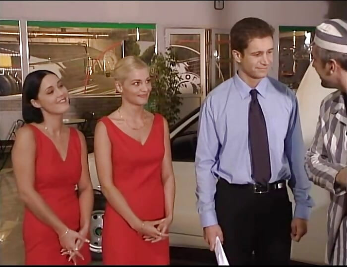Two Girls in Red Dresses Have Fun at the Car Dealer