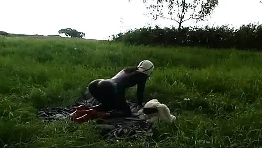 Lateksli fetiş köle yürüyor ve çimlerde dildo emiyor