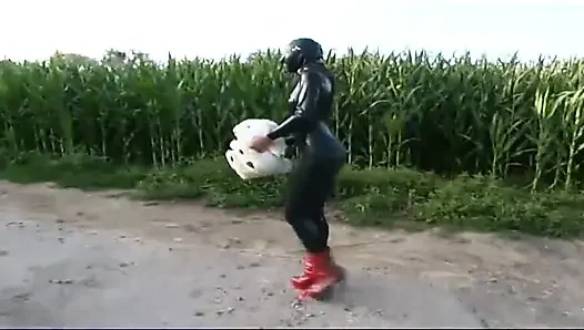 Fetish slave in latex walks and sucks a dildo on the grass