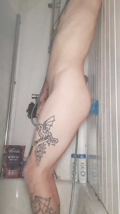Une tapette tatouée mince et pâle s’enfile un gode sous la douche