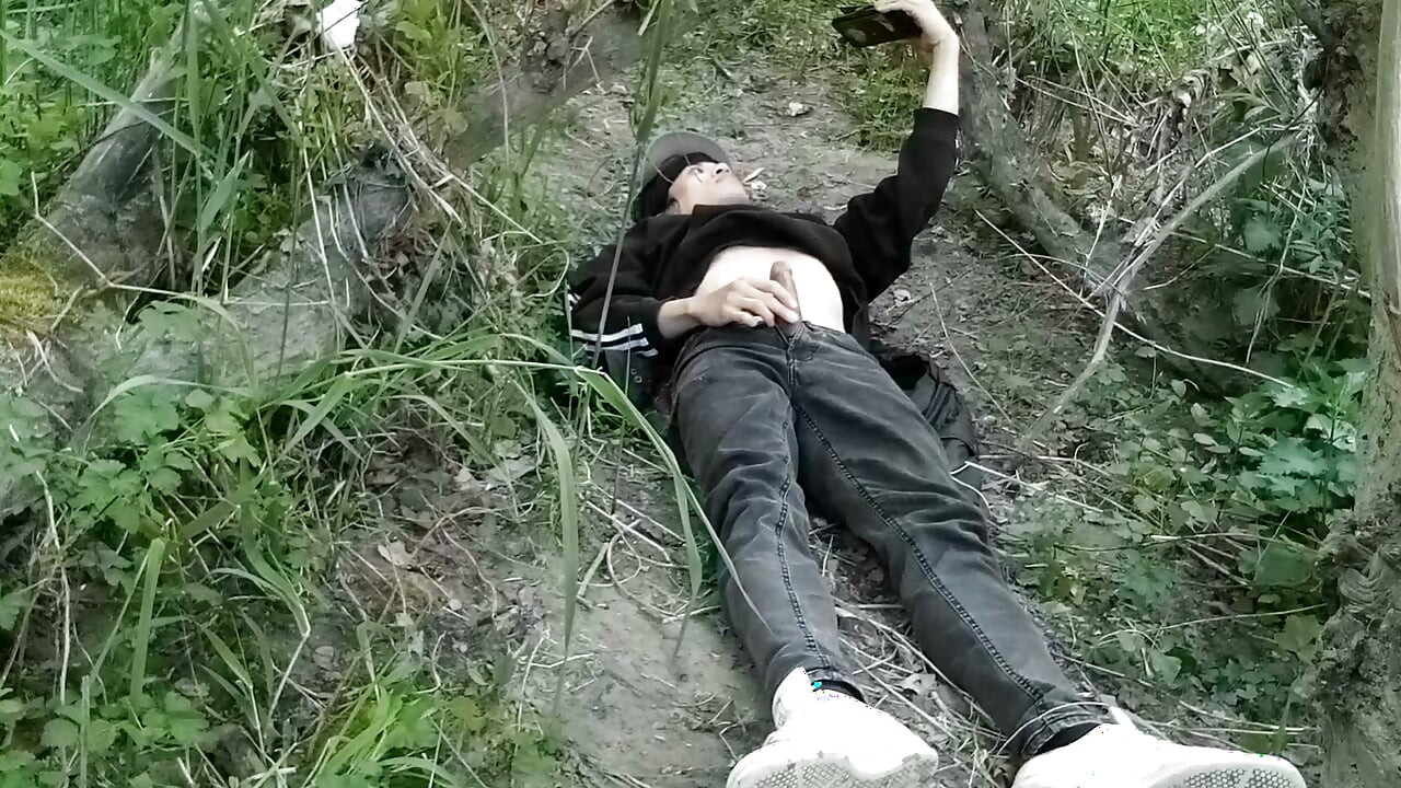 This gay twink sticks his cock through his fly to jerk off outside