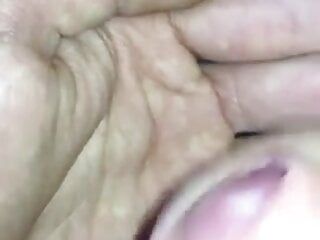 Une jeune petite bite lâche de grandes quantités de sperme sur le sperme de la main