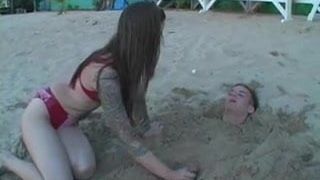 Une maîtresse joue avec un esclave sur une plage