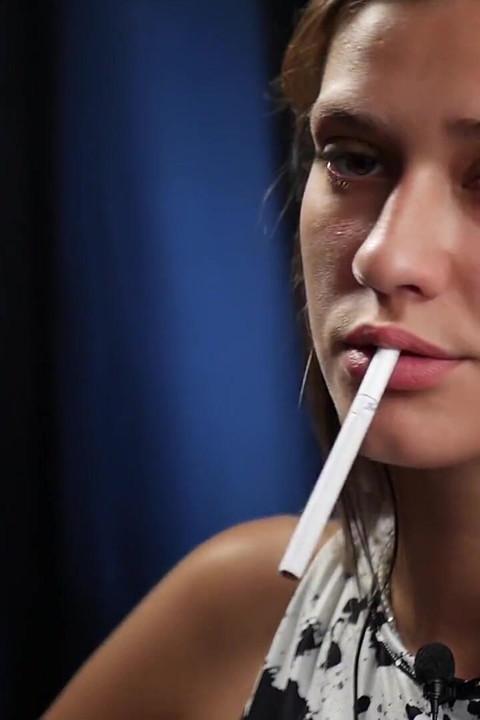Confident Slim Brunette in a Tight Patterned Dress Enjoying a Slow and Relaxed Smoking Session