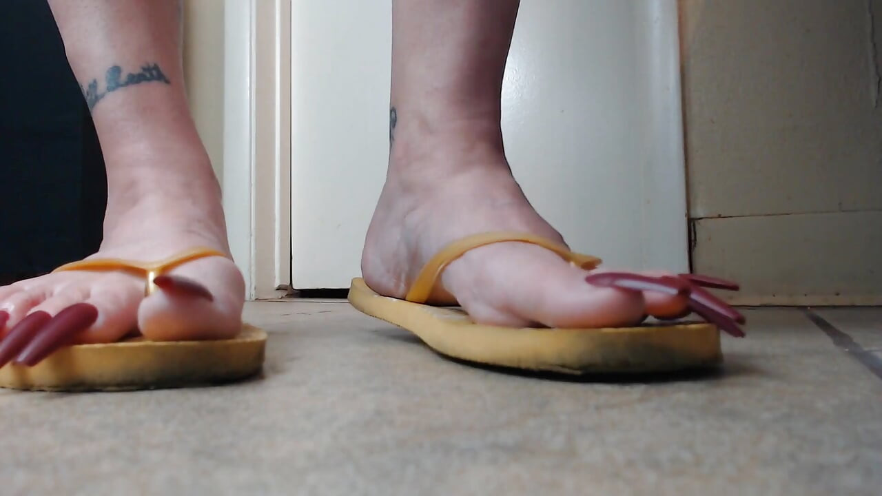 Tånegler som henger fra gule flip flops