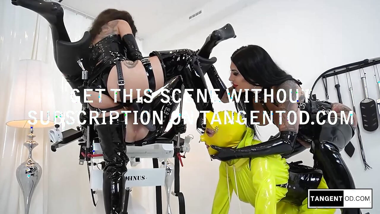 TANGENTOD Dominatoare negre din latex controlează costumul de pisică galben supus în scena scaunului medical BDSM