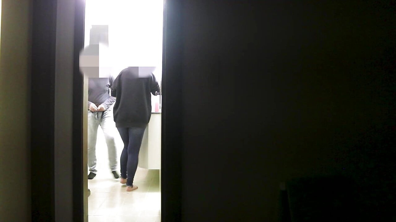 Ze geeft een pijpbeurt aan haar vriendin terwijl haar man naar een show op tv kijkt.