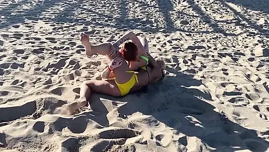 해변에서 레슬링하는 두 명의 레즈 섹시녀와 키스를 시작한 후