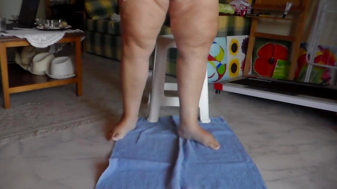 Jen está sentada em uma cadeira e fazendo xixi em uma toalha no chão