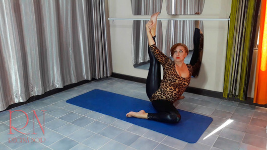 Regina Noir. Una mujer con traje de leopardo y polainas de látex está haciendo yoga en el gimnasio. Yoga en leotardos sexy.