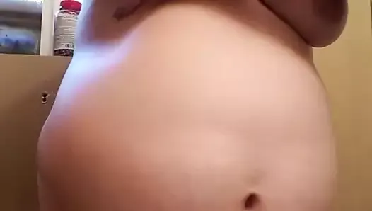 Pregnant women rubs lotion over her belly and boobs