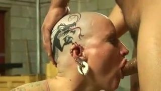 Troia tatuata con piercing alla testa calva inchiodata