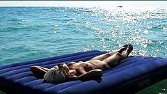 Vi en la playa cómo una chica desnuda con grandes tetas tomaba el sol sobre un colchón.