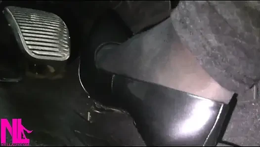 Menyadarkan dan mengemudi dengan stoking hitam dan sepatu hak tinggi abu-abu