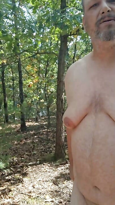 Buclatý chlap se svlékne, nechá oblečení za sebou a stříká v lese