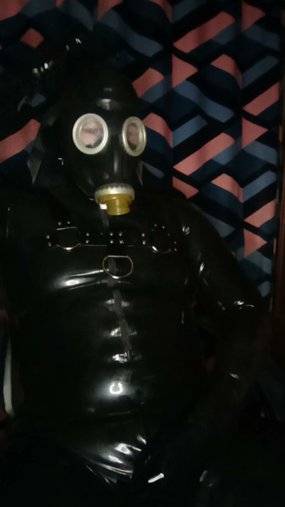 A guy in rubber pulls on a gas mask