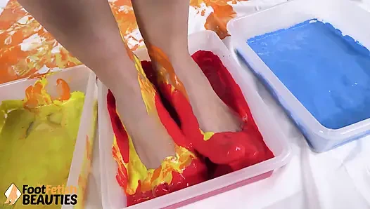 Üstsüz belle mükemmel ayaklarını ve ellerini kullanarak boyayla oynuyor