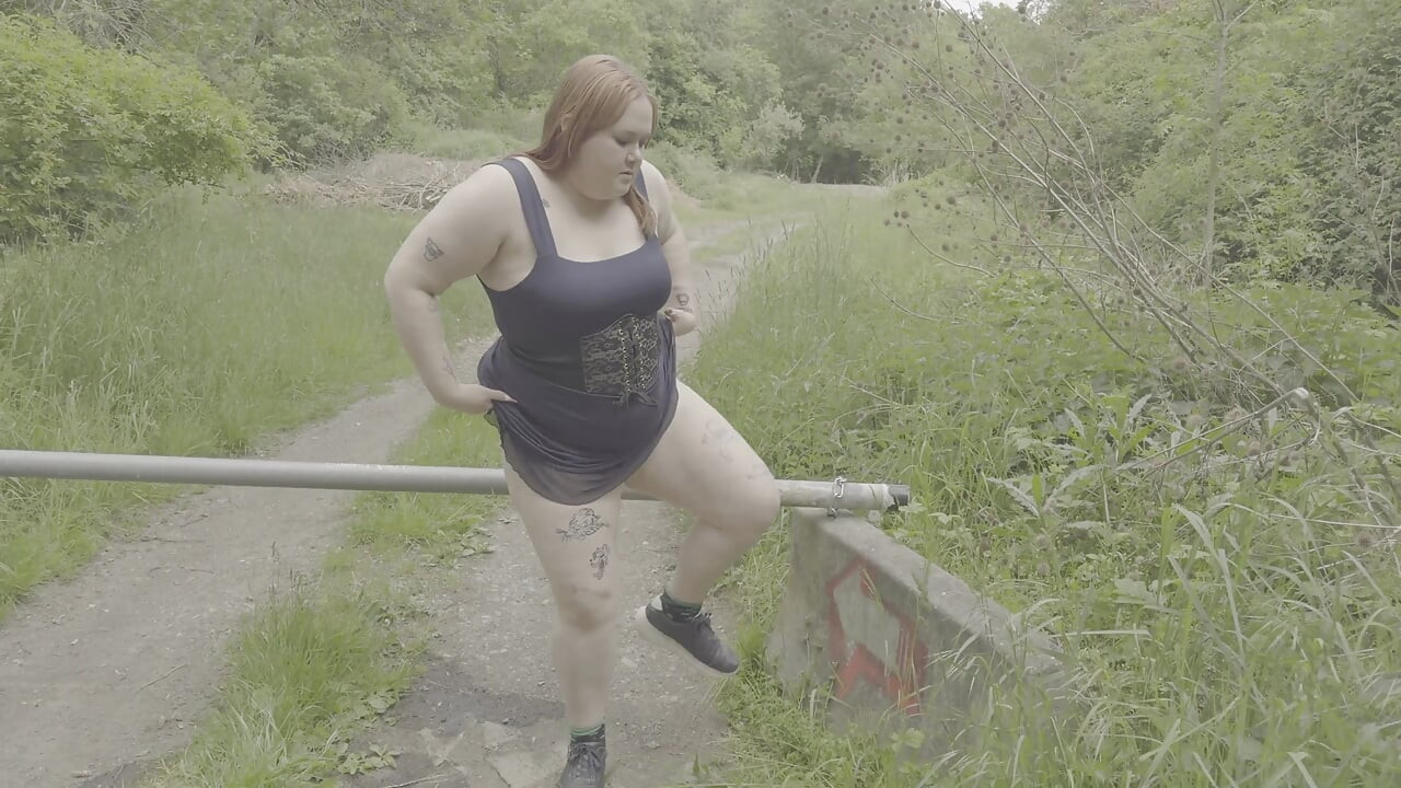 Ruiva gordinha mija ao lado de um portão