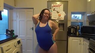 Ehefrau mit großen brüsten tanzt im engen blauen badeanzug