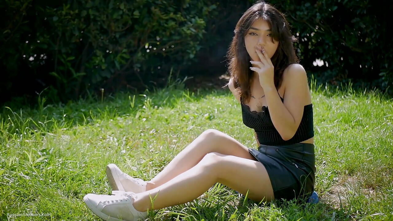 Arina está fumando um cigarro preto ao ar livre