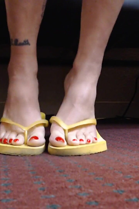 เล็บเท้าแดงกระดิกกับรองเท้าแตะสีเหลือง