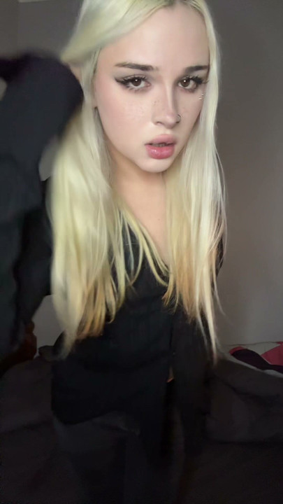 Chica trans blanca en un traje de rejilla negro se burla de su polla