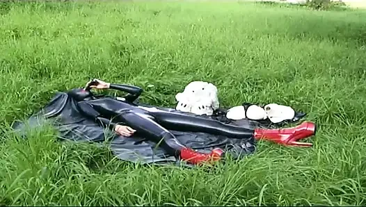 Lateksli fetiş köle yürüyor ve çimlerde dildo emiyor