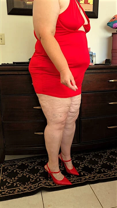 Beautiful social media model in mini red dress and high heels showing off