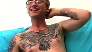 Geek aficionado con gafas y tatuajes acaricia su gran polla