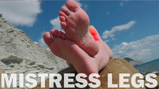 Meesteres benen op blote voeten op het zomerzeestrand