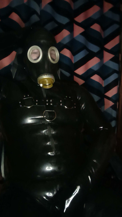 A guy in rubber pulls on a gas mask