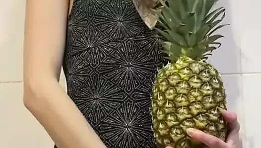 Худенькая девушка играет с ананасом
