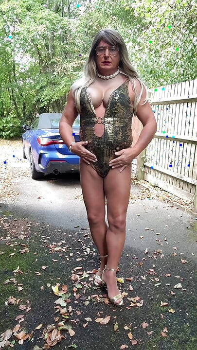 Seksi transvestit kellycd2022 u zlatnom kupaćem kostimu i štiklama čisti lišće