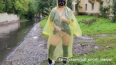 O adolescentă cu impermeabil galben își expune pizda în aer liber în ploaie